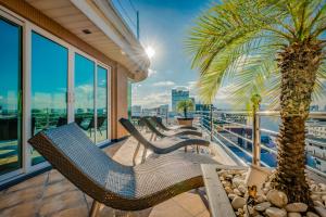 un patio con sedie e una palma sul balcone di Fields Plaza Hotel by ABC a Angeles