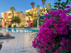 a resort with purple flowers in front of a swimming pool at Green Garden Resort in Hurghada