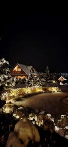 米尔科Karkonoski Klimat - domek z bali的夜晚，白雪覆盖的高尔夫球场旁有一栋房子