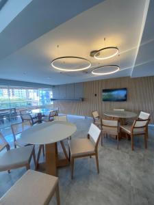 a waiting room with tables and chairs and a flat screen tv at Priority Praia grande in Praia Grande