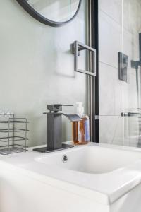 een wastafel in de badkamer met een kraan en een spiegel bij Sage & Stone Cottage in Lynchburg