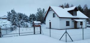 NielbarkBiały Domek Nielbark - Agroturystyka的雪中带围栏的白色房子