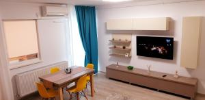 een woonkamer met een tafel en een televisie aan de muur bij ApartDecebal in Craiova