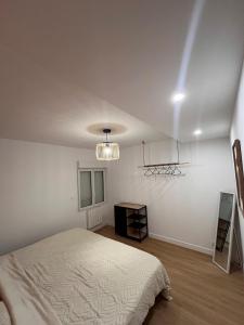 biała sypialnia z łóżkiem i żyrandolem w obiekcie Logement autonome pour 2 à 4 personnes w mieście Poitiers