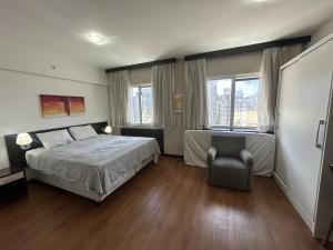 圣保罗Hotel Mercu Paraíso Benefência c garagem e cozinha 1606的卧室里有一张床和一把椅子 更多27张照片