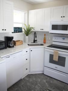 a white kitchen with white cabinets and a sink at 508 A The Shore Break Cottage in Virginia Beach