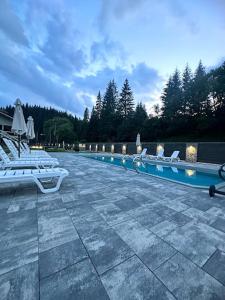 een zwembad met ligstoelen bij Садиба "Hutsulyana" in Dobrovelychkivka