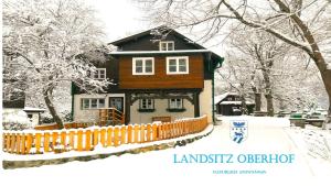 a wooden house with a fence in the snow at LANDSITZ OBERHOF petit hôtel in Muggendorf