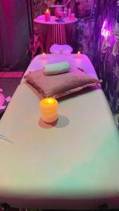 a white bed with a candle on top of it at Un Mirage Tropical - Bulles , Spa & Détente en Bord de Loire in Saint-Clément-des-Levées
