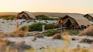 a woman standing in front of tents in the desert at Sal Salis Ningaloo Reef in Exmouth