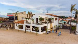 a white building with palm trees and people sitting in chairs at Casa Galo Pretto in Galinhos