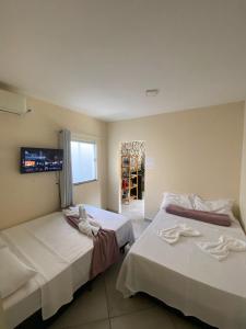 two beds in a room with a tv on the wall at Pousada Vista da Serra - Suzart in Lençóis