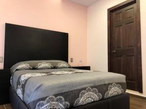 a bedroom with a large bed with a black headboard at Hotel Rivas in Tequila