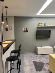 a bar with two stools and a tv on a wall at Casa aconchegante em Aracaju na Aruana in Aracaju