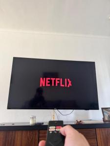 圣拉斐尔Complejo de Cabañas Quintana Cochera Cocina Wifi Smartv Aire Acondicionado的电视机前遥控器的人