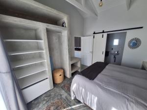 a bedroom with a bed and white cabinets and shelves at 66onjennings Strand in Strand