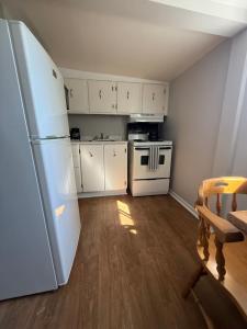 eine kleine Küche mit weißen Schränken und einem Kühlschrank in der Unterkunft Elizabeth Ave Apartments - Loft Apartment in St. John's