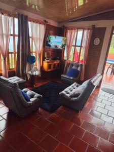 Una sala de estar con sofás y un televisor de pantalla plana. en Glampin y Cabañas MAGISTRAL VILLA EL EDEN, en Cali
