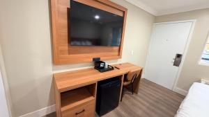 a room with a desk with a television on a wall at Border Plaza Hotel in San Diego