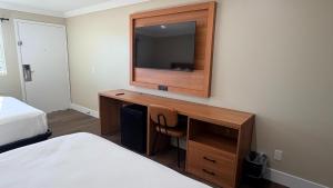 a hotel room with a desk with a television on the wall at Border Plaza Hotel in San Diego