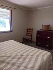 LavingtonOmann Cottage的一间卧室，里面有一张床、一把椅子和一扇窗户