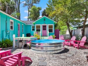 Un patio con sillas rosas y una casa azul. en Blue Cat, en Tybee Island