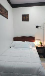 un letto bianco in una camera bianca con tavolo di Cozy Studio Rohrmoser a San José