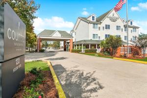a building with a sign in front of a street at Country Inn & Suites by Radisson, Covington, LA in Covington