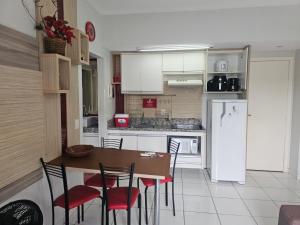 a kitchen with a table and chairs and a refrigerator at Frente ao Parque da Lagoa Quente Entrada NÃO INCLUSA Aptos Particulares com varanda in Caldas Novas
