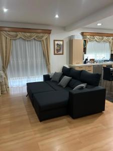 ein Wohnzimmer mit einer schwarzen Couch und einer Küche in der Unterkunft Alojamento Luna in Porto Judeu + 22 Fotos