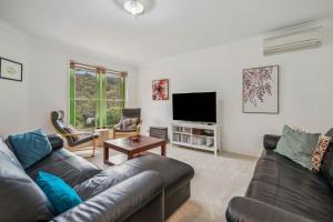 Una sala de estar con un sofá y un televisor en Minnehaha, en Katoomba