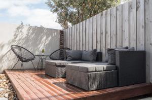 a patio with a couch and a chair on a wooden deck at Hide and Sea in Seaford