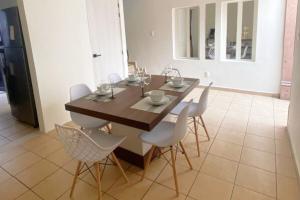 a dining room with a wooden table and white chairs at Casabel - Downtown Querétaro in Querétaro