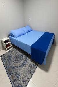 um quarto com uma cama com lençóis azuis e um tapete em Casa azul - próx de Nazaré com Split e Wi-Fi em Belém