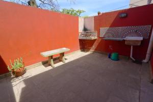 a bench sitting next to a red wall with a sink at Los colibríes in Necochea