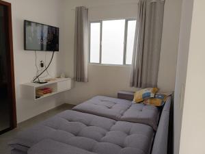 a bedroom with a bed and a tv and a window at Refúgio do Mar in Japaratinga
