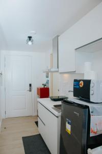 eine Küche mit weißen Schränken und einem schwarzen Kühlschrank in der Unterkunft Stefan Staycation @ Azure North in San Fernando