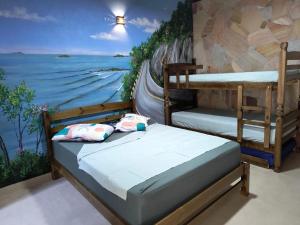 two bunk beds in a room with a painting at Guaraú Surf House Chalés in Peruíbe