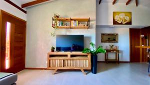 a living room with a tv and a table at JanHouse Ilhabela in Ilhabela