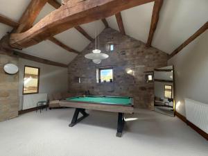 a pool table in a room with a stone wall at Grains Barn Farm in Burnley