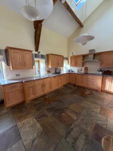 a large kitchen with wooden cabinets and a tile floor at Grains Barn Farm in Burnley