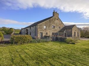 an old stone building with a grass field in front of it at Grains Barn Farm in Burnley