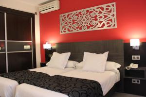 Habitación de hotel con 2 camas y pared roja en Hotel Venecia en Sevilla