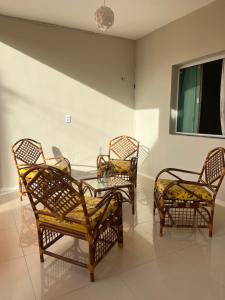 drie rieten stoelen en een glazen tafel in een kamer bij Aconchego Paracuru in Paracuru