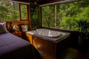 Rio FortunaにあるMaravilhoso Chalé em Urubiciの窓付きのベッドルーム(大型バスタブ付) +6枚の写真