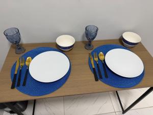 a table with white plates and forks and spoons at AmazHost - Casa azul próxima da Basílica de Nazaré in Belém