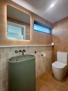 a bathroom with a sink and a toilet and a mirror at Pacific Sun Bargara in Bargara