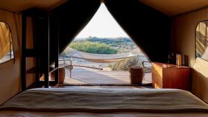 a bedroom with a bed and a view of a boardwalk at Sal Salis Ningaloo Reef in Exmouth