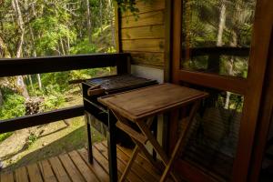 Rio FortunaにあるMaravilhoso Chalé em Urubiciの窓のある小屋のポーチにあるグリル