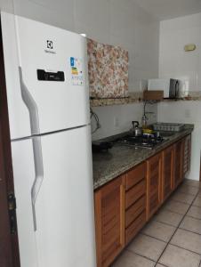 a kitchen with a white refrigerator and a stove at Torres a mais bela praia gaúcha in Torres